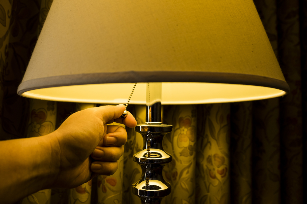 Warm tone imaged of hand turning of lamp in bedroom