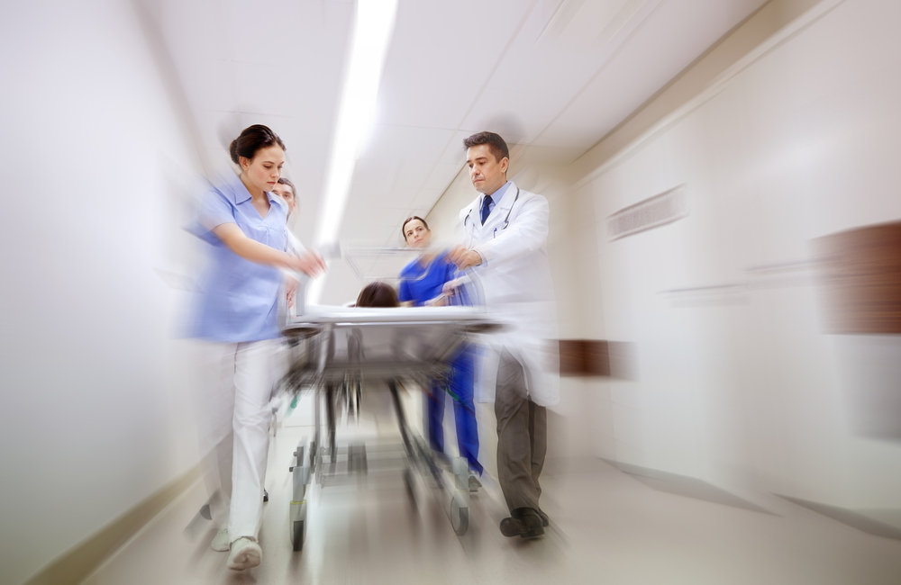 health care, reanimation and medicine concept - group of medics or doctors carrying unconscious woman patient on hospital gurney to emergency (motion blur effect)
