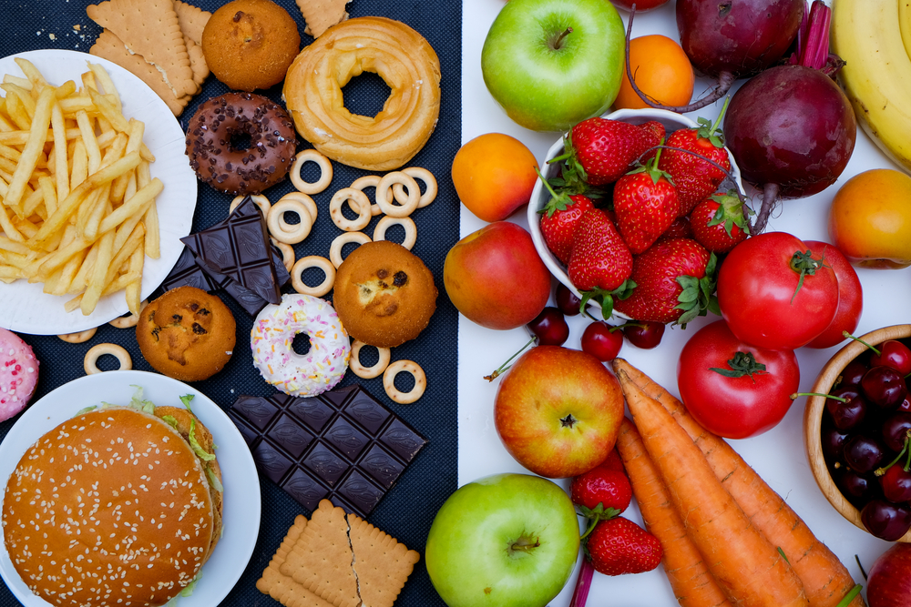 Concept photo of healthy and unhealthy food. Fruits and vegetables vs donuts,sweets and burgers
