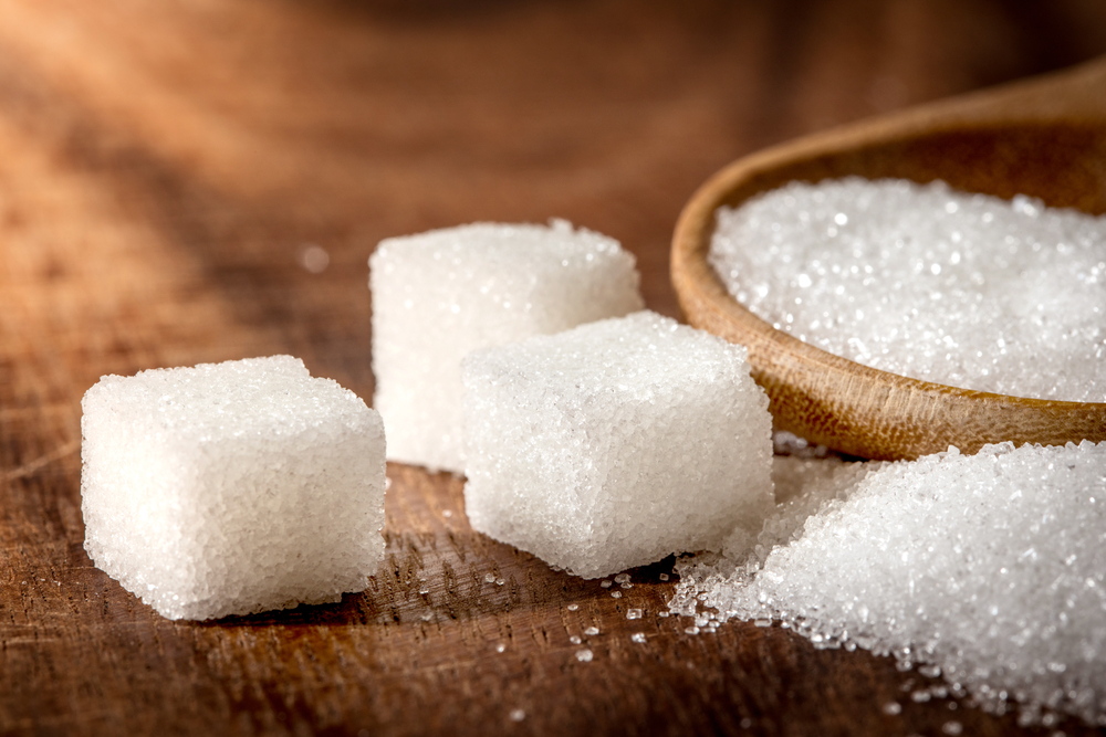 Close up the sugar cubes and cane in wooden spoon on the table ,retro color tone
