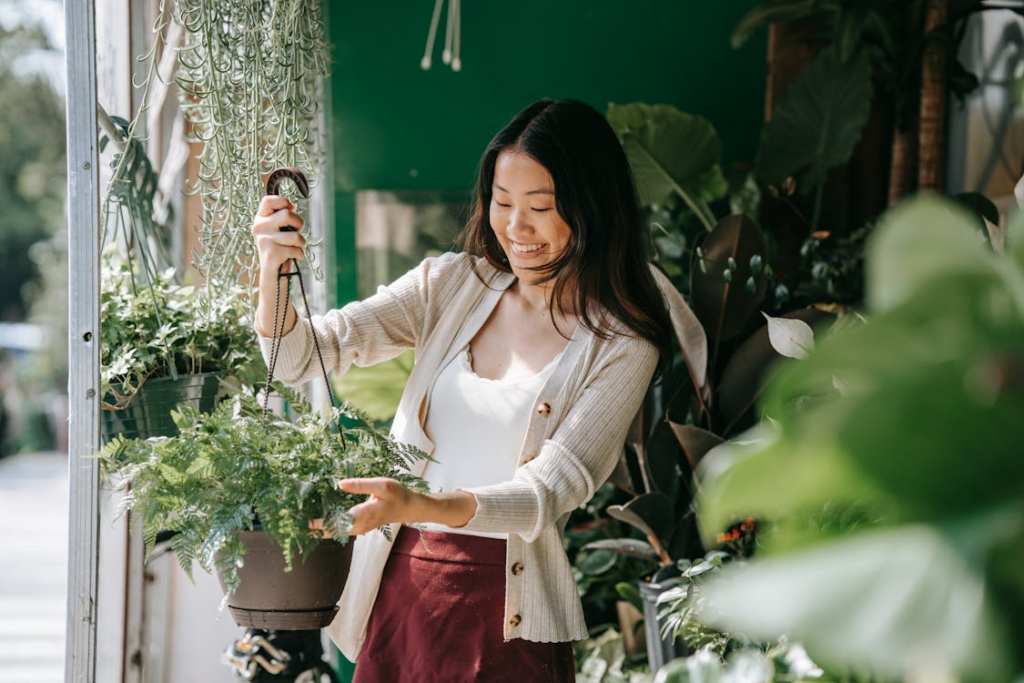 Happy Woman in White Long Sleeves holding a Pot of Plant