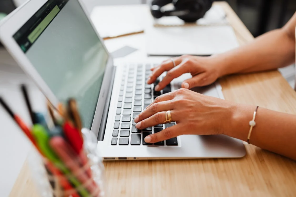 Person Using a Laptop on Brown Wooden Table