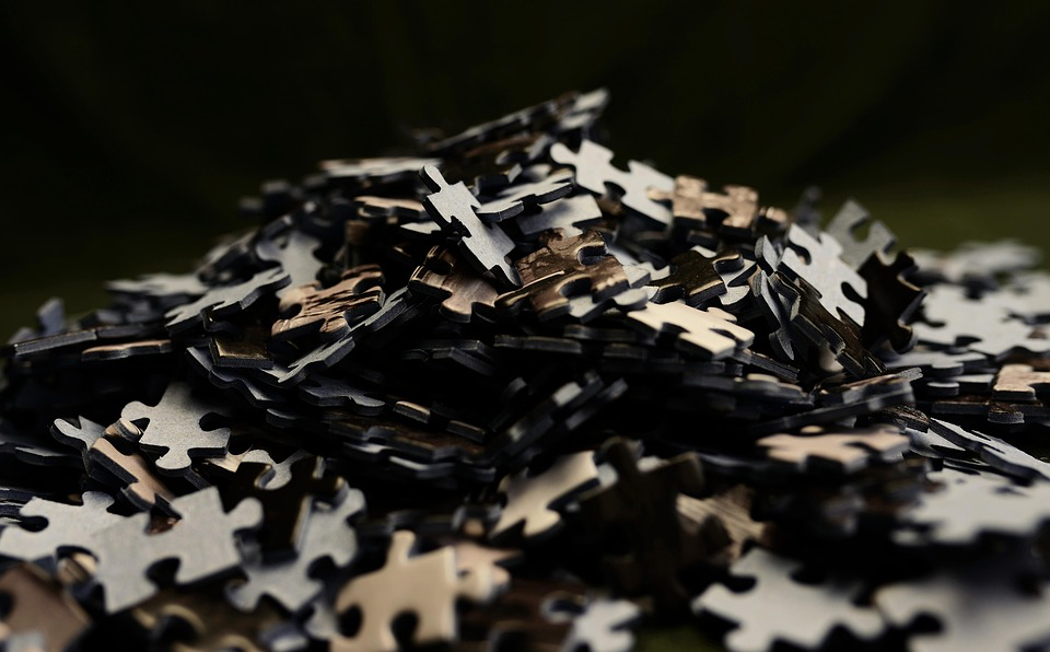 A pile of scattered jigsaw puzzle pieces in black and white, symbolizing the complex and fragmented nature of memory and cognitive function in dementia. Puzzles also represent the challenges of piecing together care plans and understanding the various factors that influence the progression of the condition.