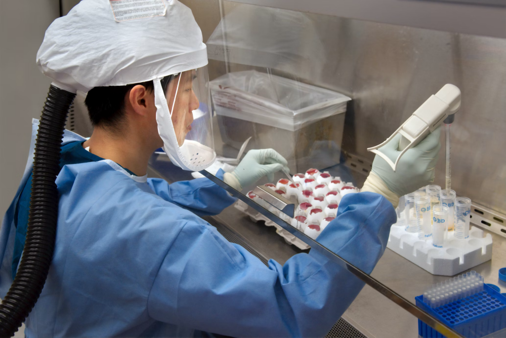 Scientist in protective equipment working in a laboratory setting, representing research efforts to combat pandemics and bioterrorism risks.