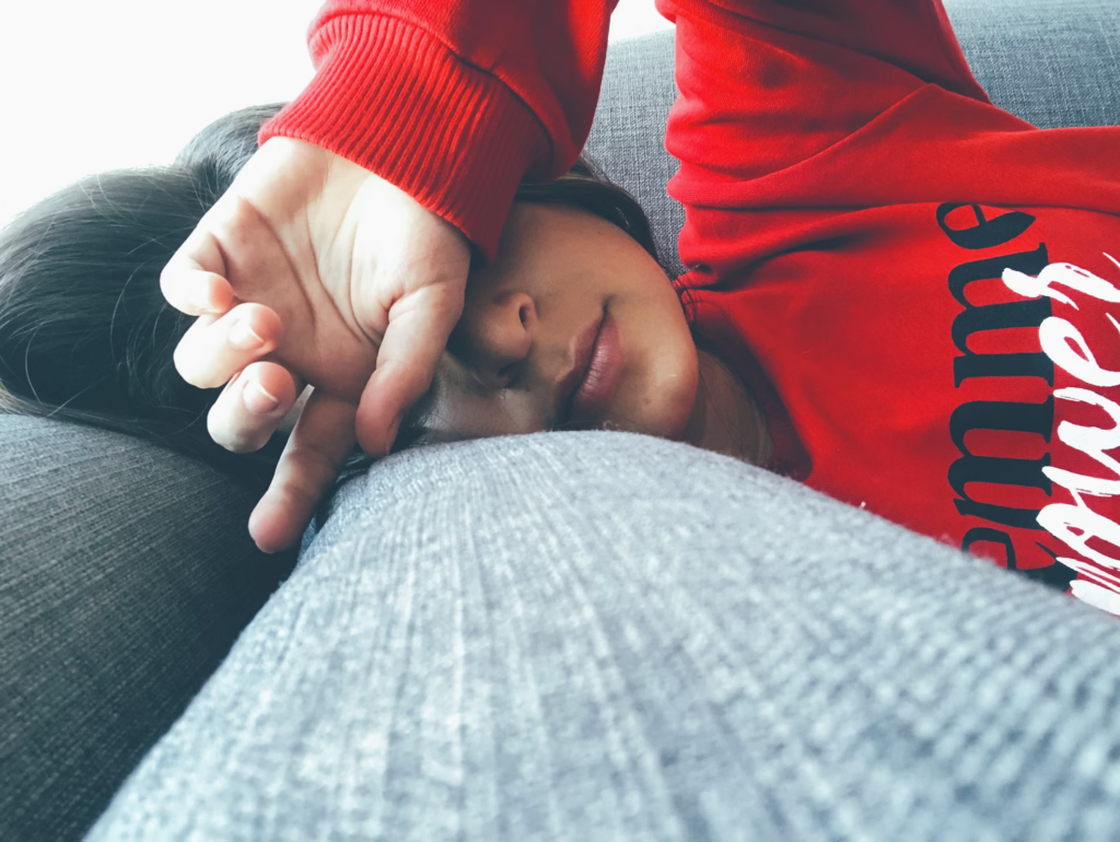 Person lying on couch appearing tired and lethargic, representing the energy dips.