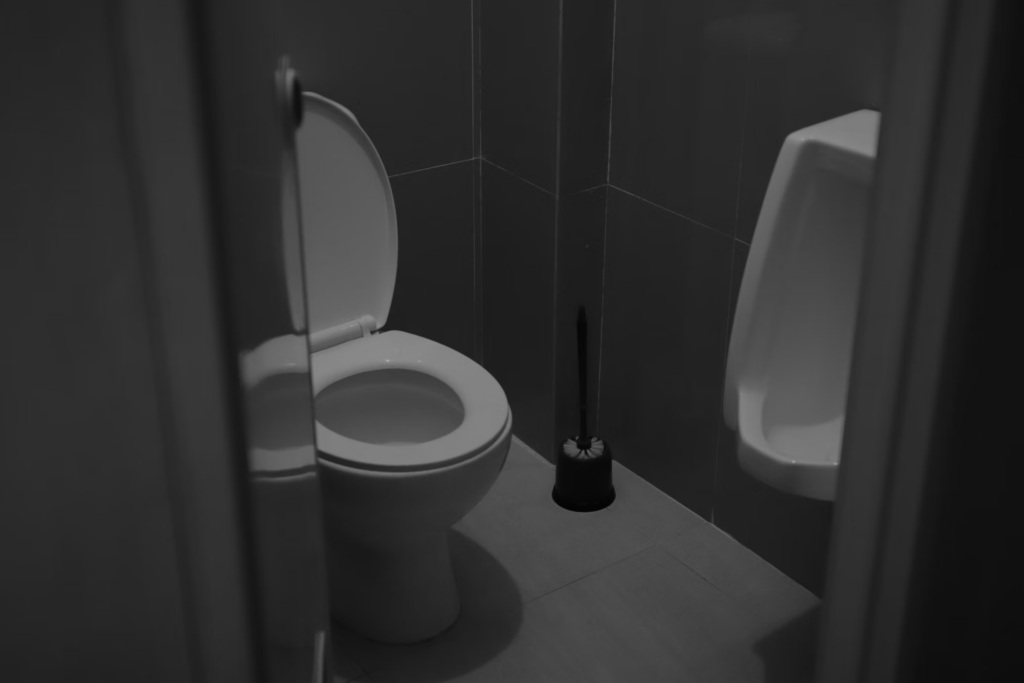 Bathroom toilet and urinal in dark lighting, representing digestive issues that may occur with low-fiber foods like instant ramen noodles.