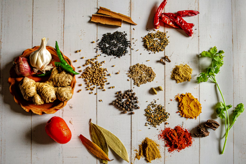 Various herbs, spices, and fresh ingredients displayed on a wooden surface, for creating healthier homemade broths to replace sodium-heavy ramen flavoring packets.