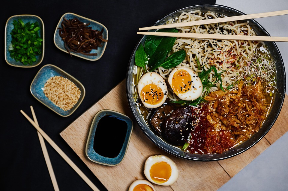Traditional ramen bowl with pork slices, soft-boiled egg, and vegetables, demonstrating a more nutritious version compared to instant ramen noodles.