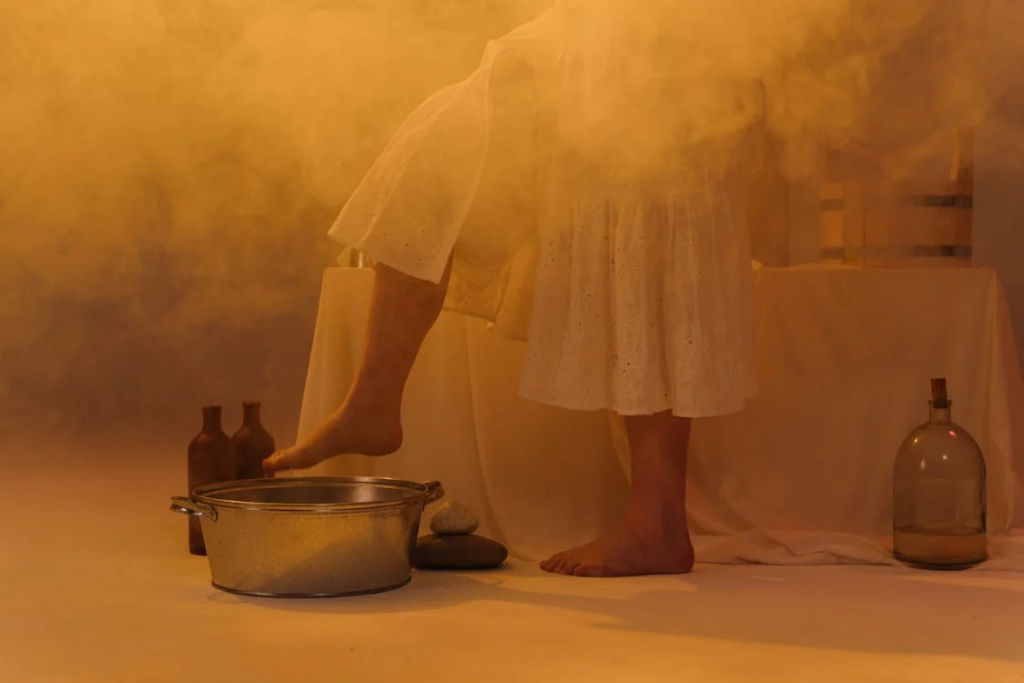 A Person in White Skirt About to Put Her Feet on the Metal Basin