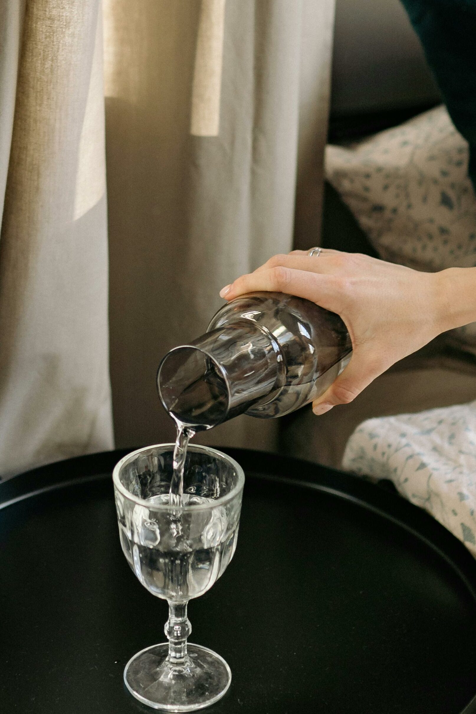 A Hand Pouring Water on the Glass