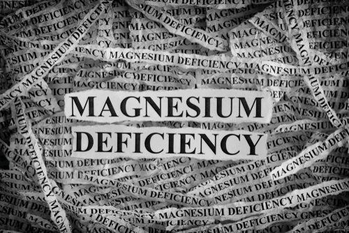 Magnesium Deficiency. Torn pieces of paper with words Magnesium Deficiency. Concept Image. Black and White. Closeup.