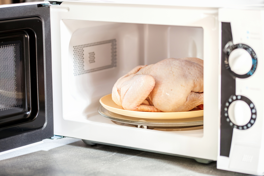 The defrozen raw chicken in the microwave. Selective focus.