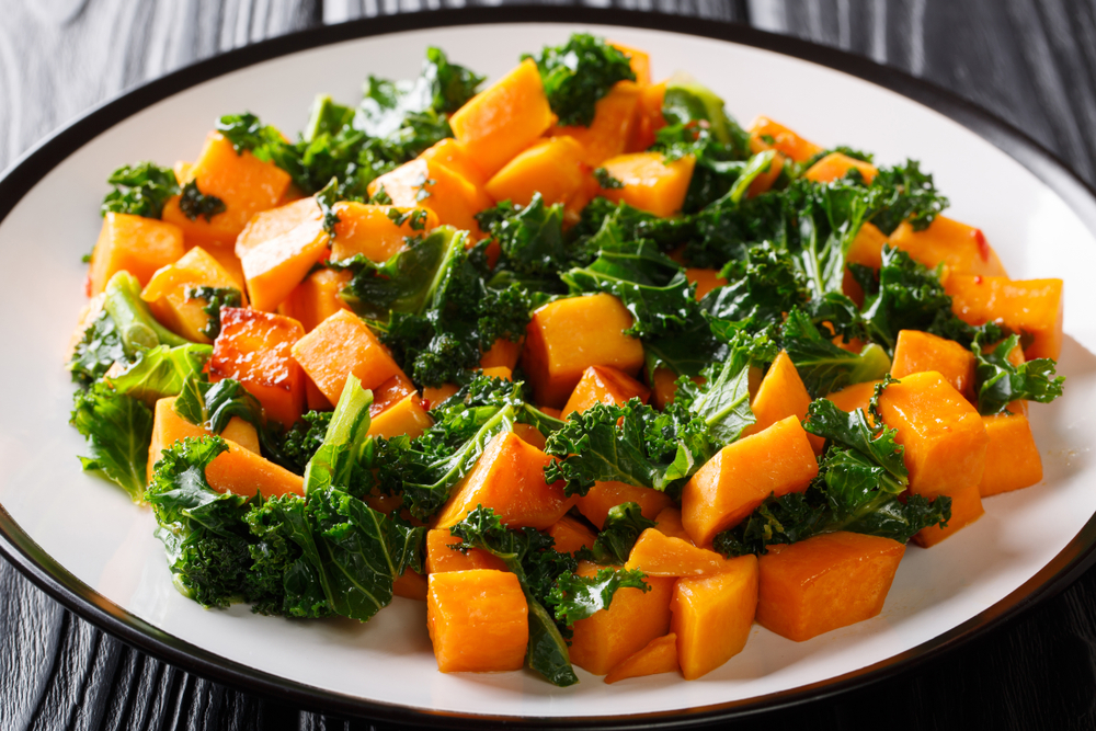 Healthy eating fried sweet potatoes with cabbage kale close up on a plate on the table. horizontal 
