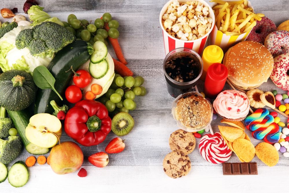healthy or unhealthy food. Concept photo of healthy and unhealthy food. Fruits and vegetables vs donuts,sweets and burgers on table
