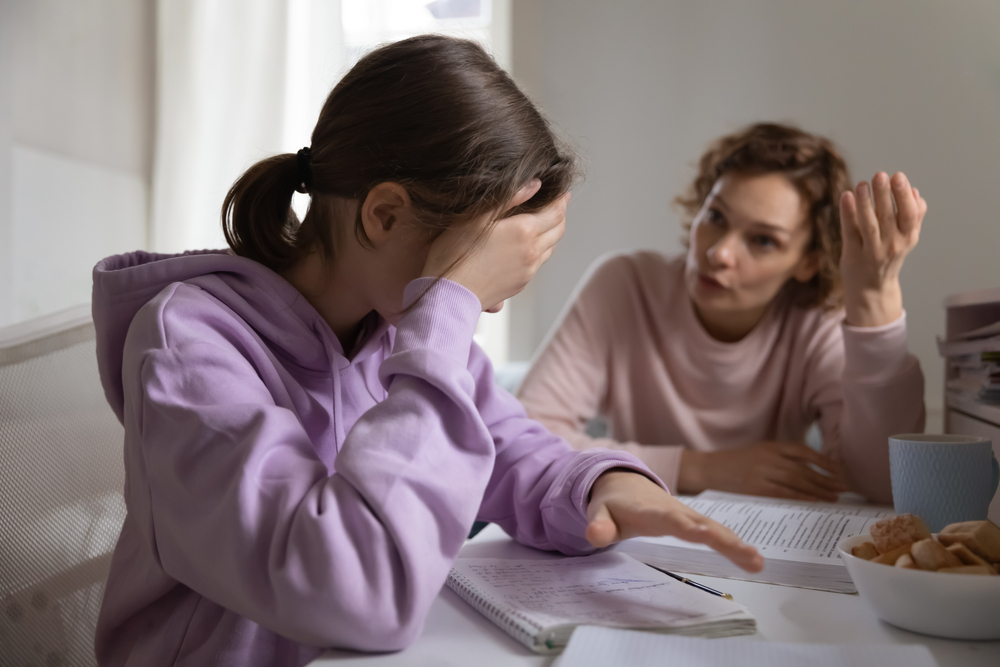 Angry adult mother scolding lazy teen daughter for bad school results at home. Frustrated mum talking to upset teenage girl arguing disciplining child must study. Parent and children conflicts concept
