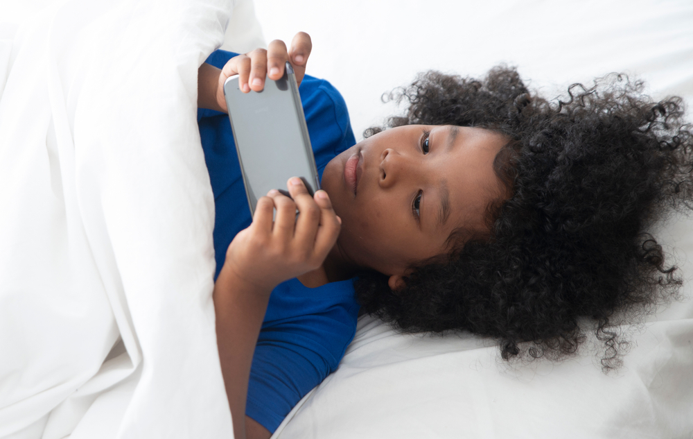 internet and network addiction. Little child is Nomophobia syndrome. It is cause of Attention deficit hyperactivity disorder. African American play the game
