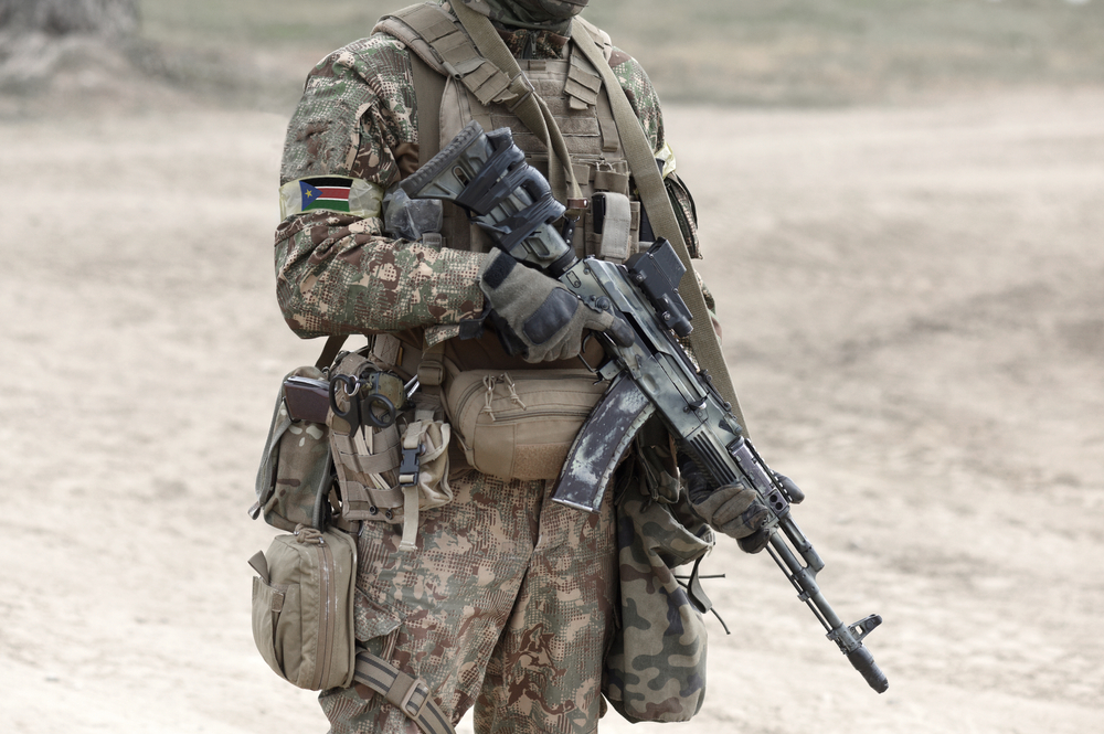 Soldier with assault rifle and flag of South Sudan on military uniform. Collage. 
