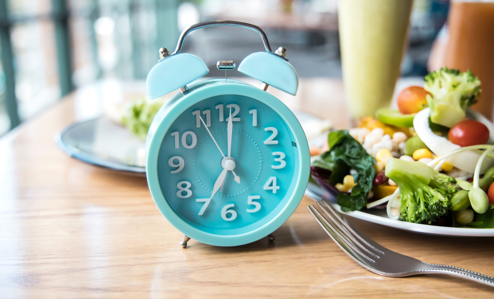 Alarm clock of blue which schedule of meal for weight loss and Intermittent fasting concept