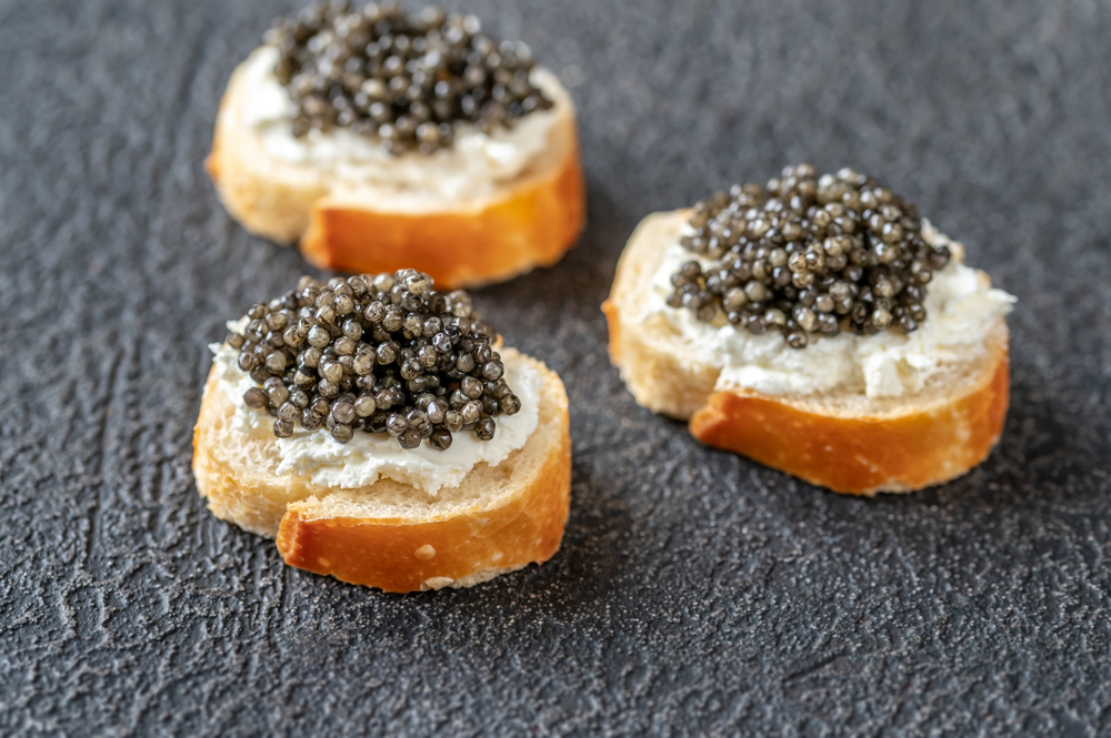 Baguette slices with cream cheese and black caviar