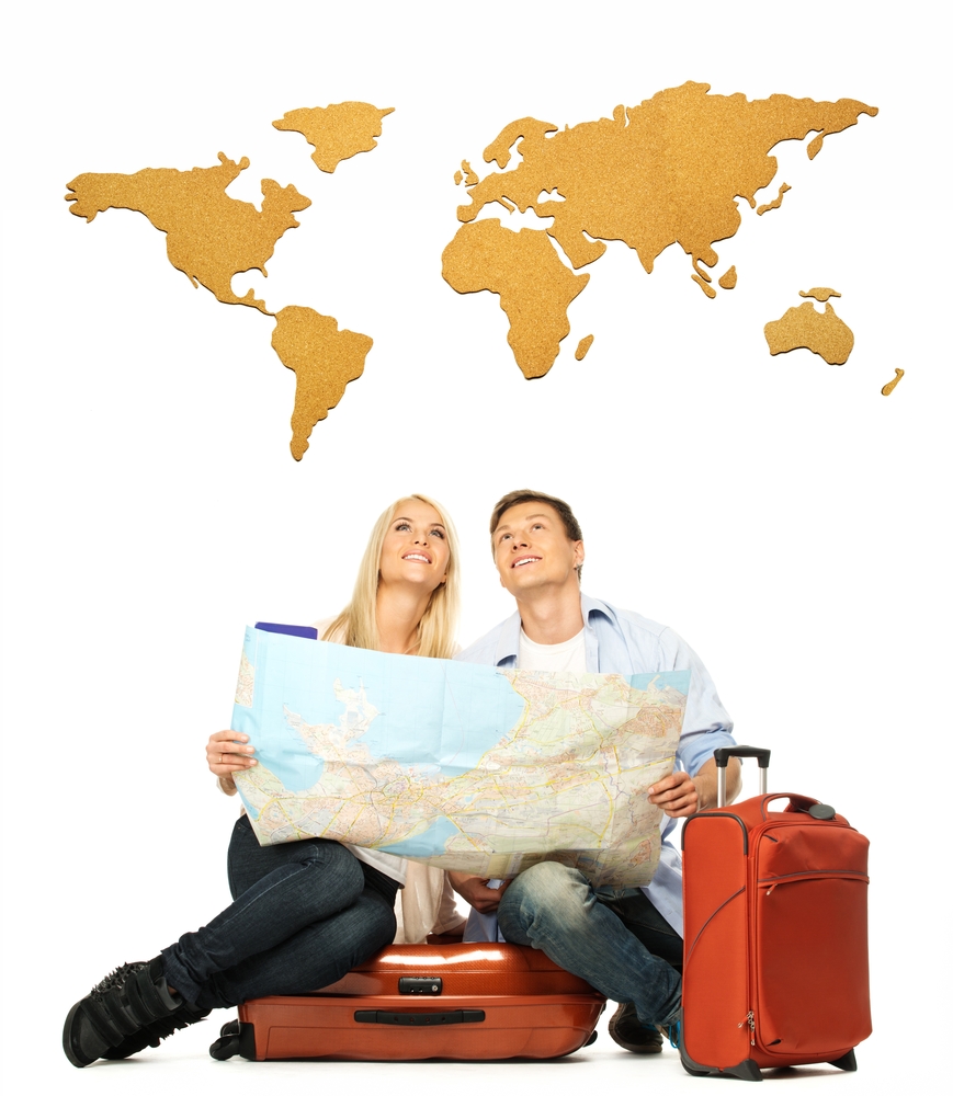 Smiling beautiful young couple with a map sitting on a suitcase
