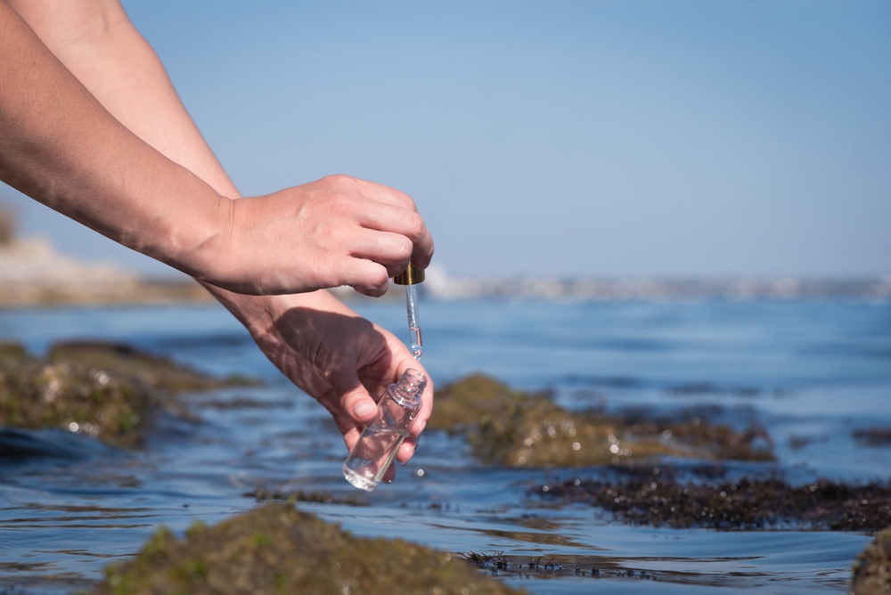 Sea water pollution concept. The scientist is taking  water sample of sea water close up concept.