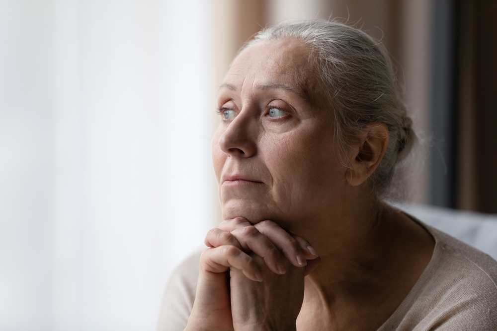Thoughtful bored older 70s woman looking at window, feeling depressed, frustrated, lonely, suffering form memory loss, dementia, Alzheimer disease, mental disorder. Old age problems concept
