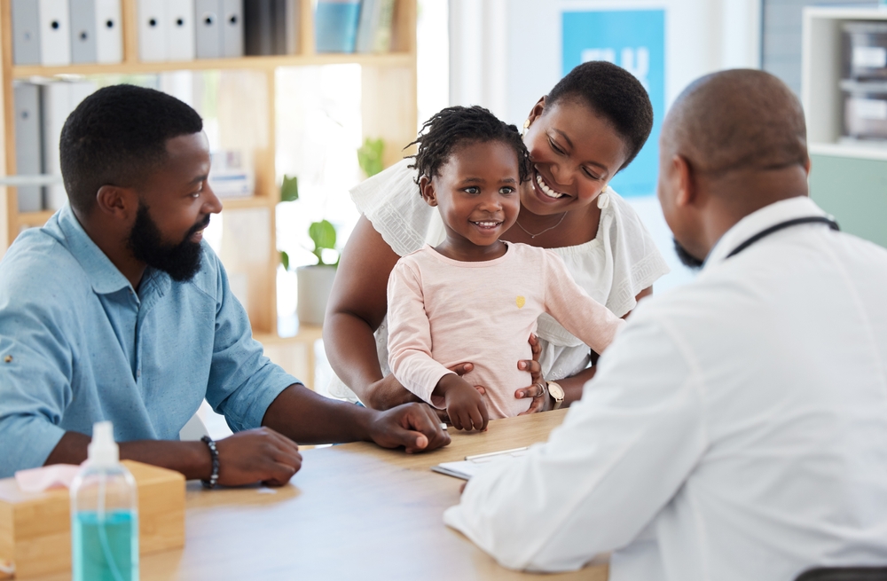 Black family, girl and consulting doctor in hospital, healthcare and medical room with mother, father and kids. Smile, happy and trust with pediatrician employee, worker and children medicine support
