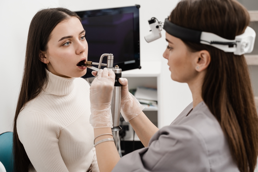 Female doctor otolaryngologist with cryosprayer. ENT doctor is spraying nitrogen for cryotherapy. Cryo procedures for mucosal renewal and treatment of chronic pharyngitis and tonsillitis