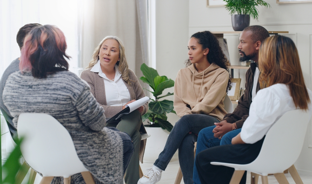 Counseling, group and psychology discussion with group of diversity people in therapy for depression, stress and anxiety. Men and women healing during psychologist meeting talking about mental health
