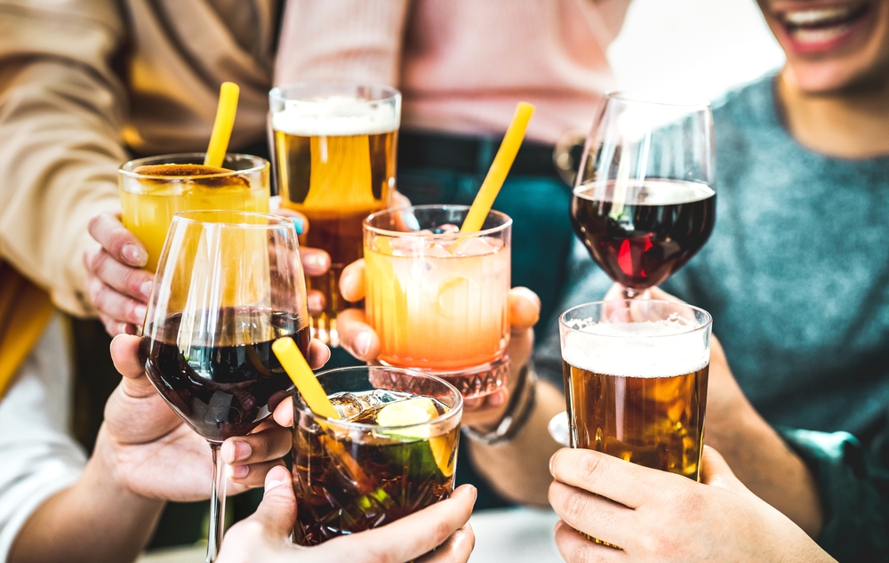 Friends hands toasting fancy cocktails - Young people having fun together drinking beer and wine at happy hour - Social life style party time concept on vivid filter - Focus on lower cuba libre drink
