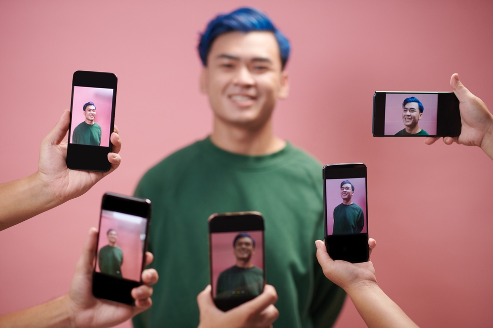 Hands of subscribers photographing influencer on smartphones at meetup