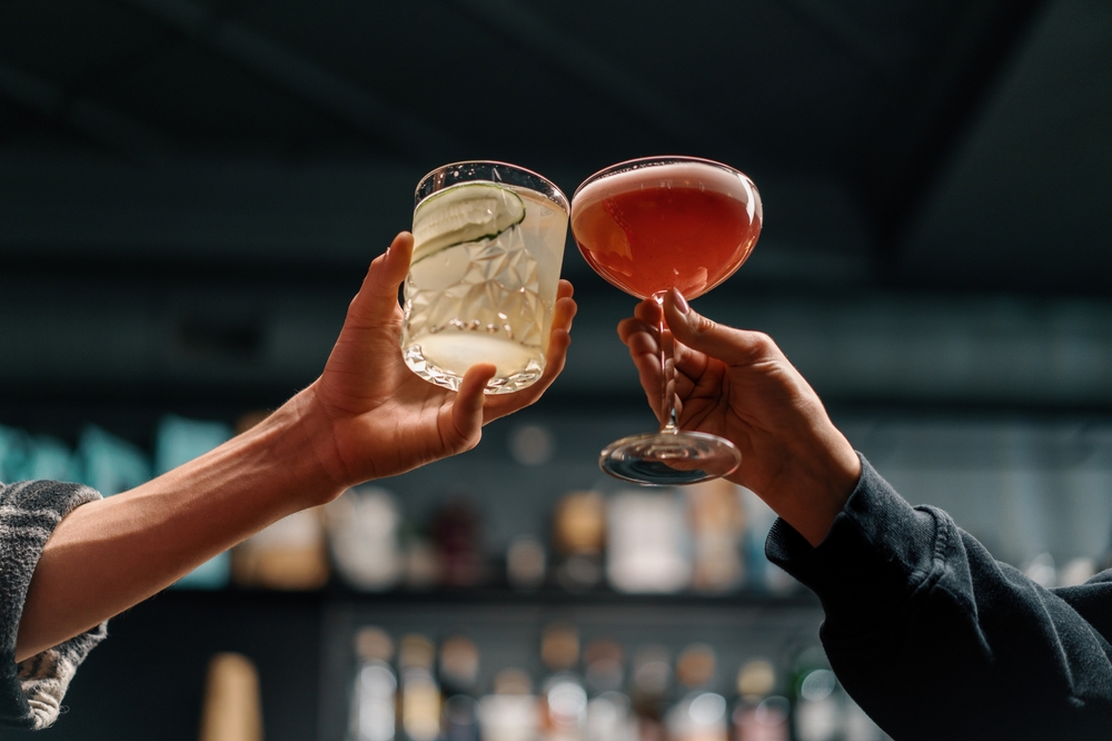 Close up of two people cheering cocktails in bar or disco club drinks and cocktails concept
