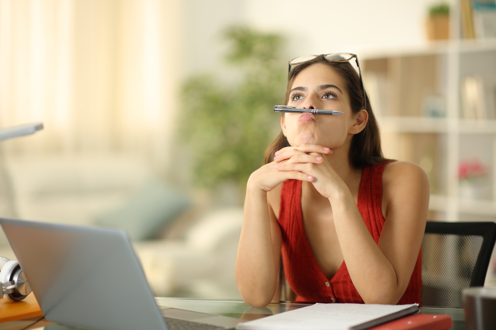Bored student with laptop wasting time sitting at home
