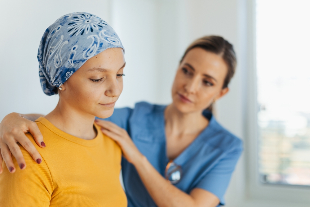 Teenage oncology patient talking with doctor. Oncologist treating teen girl with cancer and provide emotional support, helping her with anxiety and depression.
