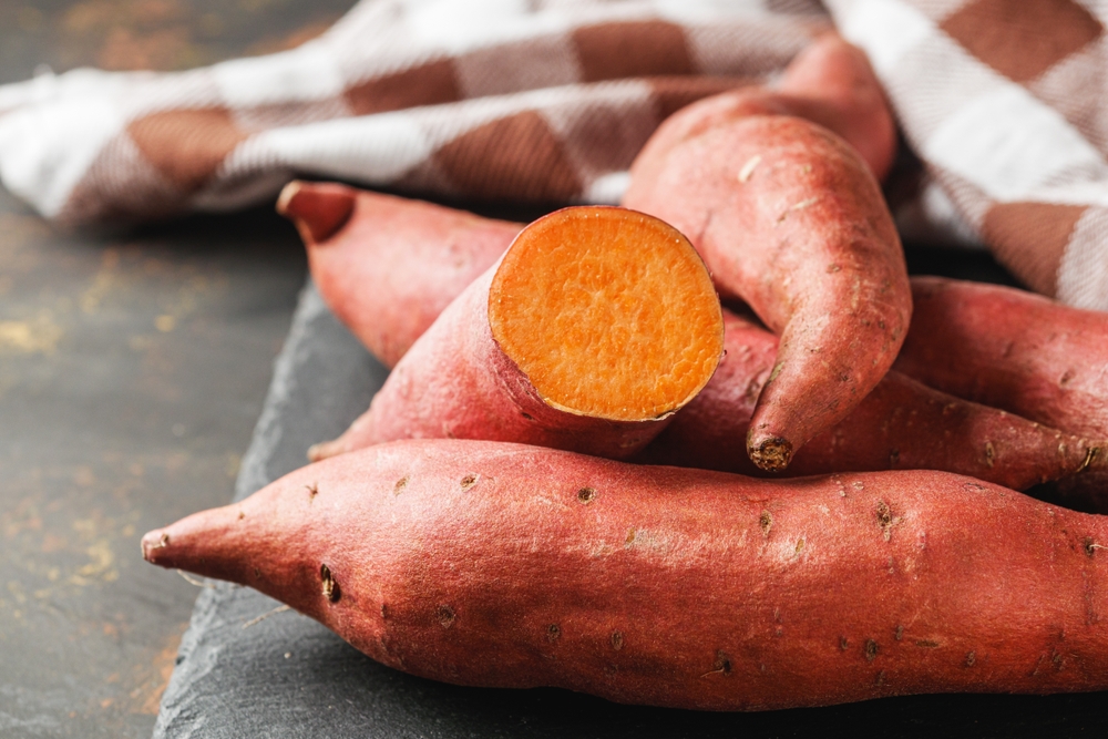 fresh sweet potatoes on a dark rustic background.

