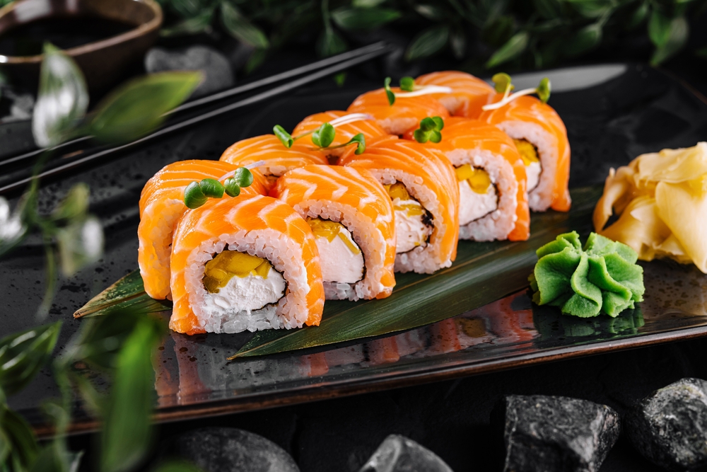 Gourmet salmon sushi rolls served on a black plate with garnishes, ready for a fine dining experience