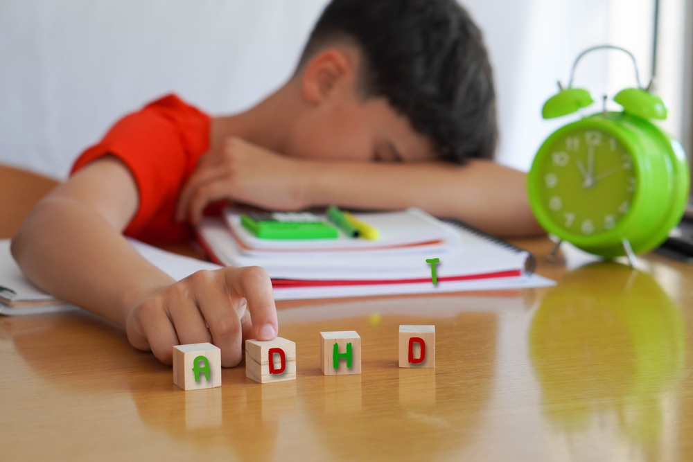 child surrounded by books and notebooks frustrated, with the acronym ADHD, represents the disease Attention Deficit Disorder and the difficulties it entails in school life.
