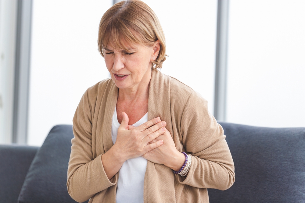 Woman with pain on heart, Mature female presses hand to chest has heart attack suffers from unbearable pain