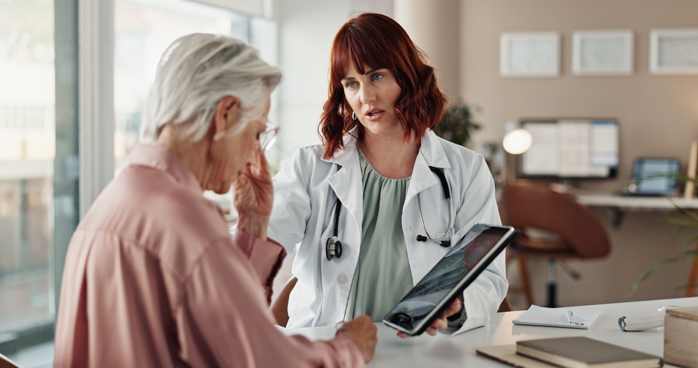 Sad, senior woman and doctor with tablet for results, consultation and support for cancer diagnosis in office. Bad news, elderly patient and medical professional with digital app for healthcare exam
