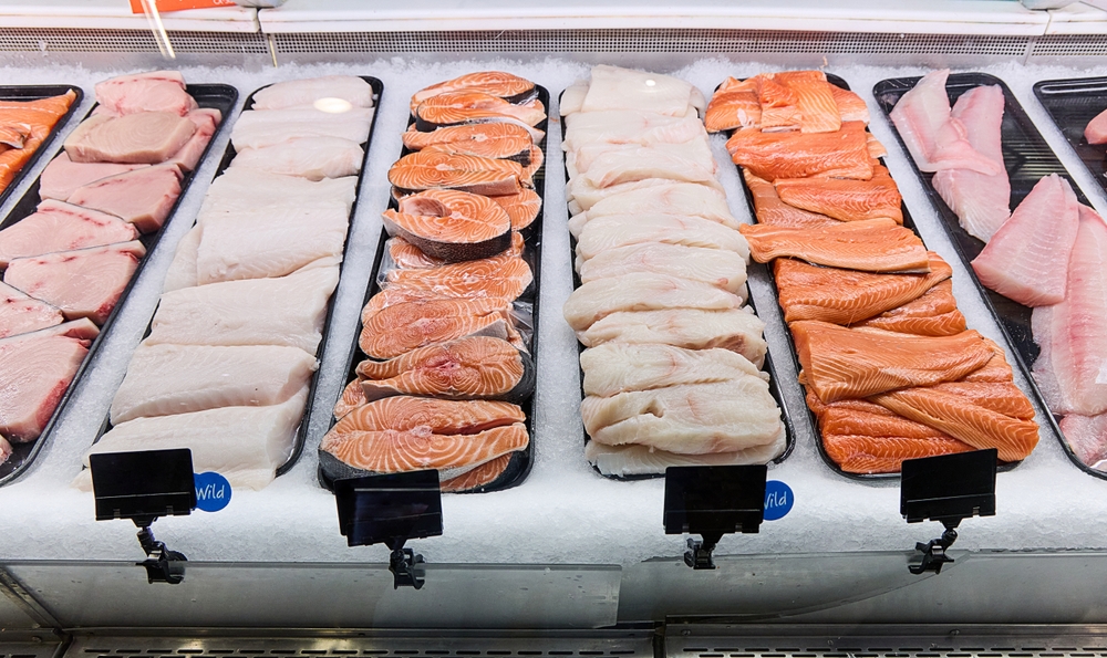A display case of a fish shop that displays a variety of fresh and trimmed fish

