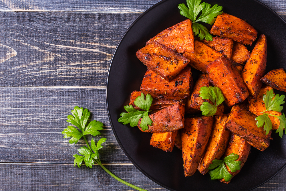 Homemade Cooked Sweet Potato with spices and herbs on dark background.
