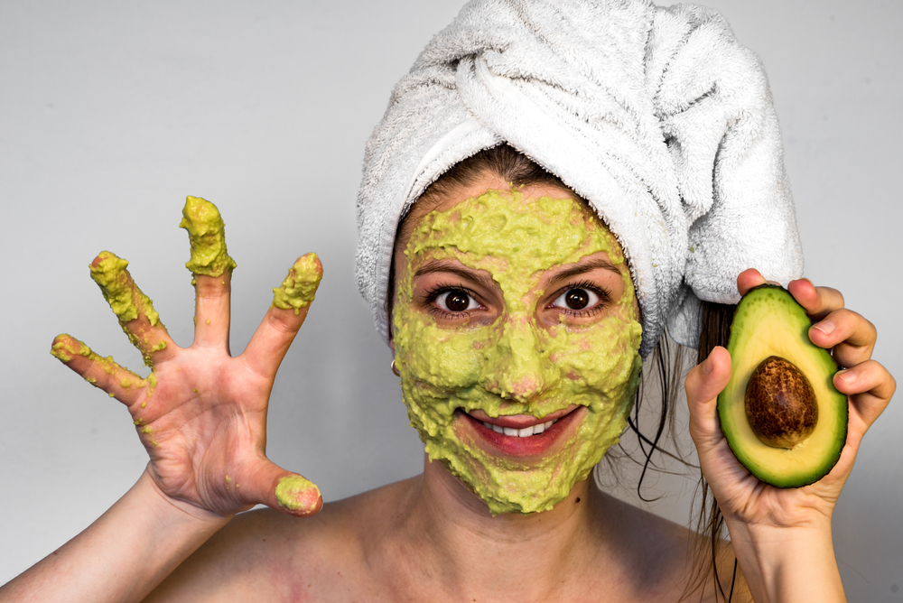 Avocado face mask with green color on smiling woman