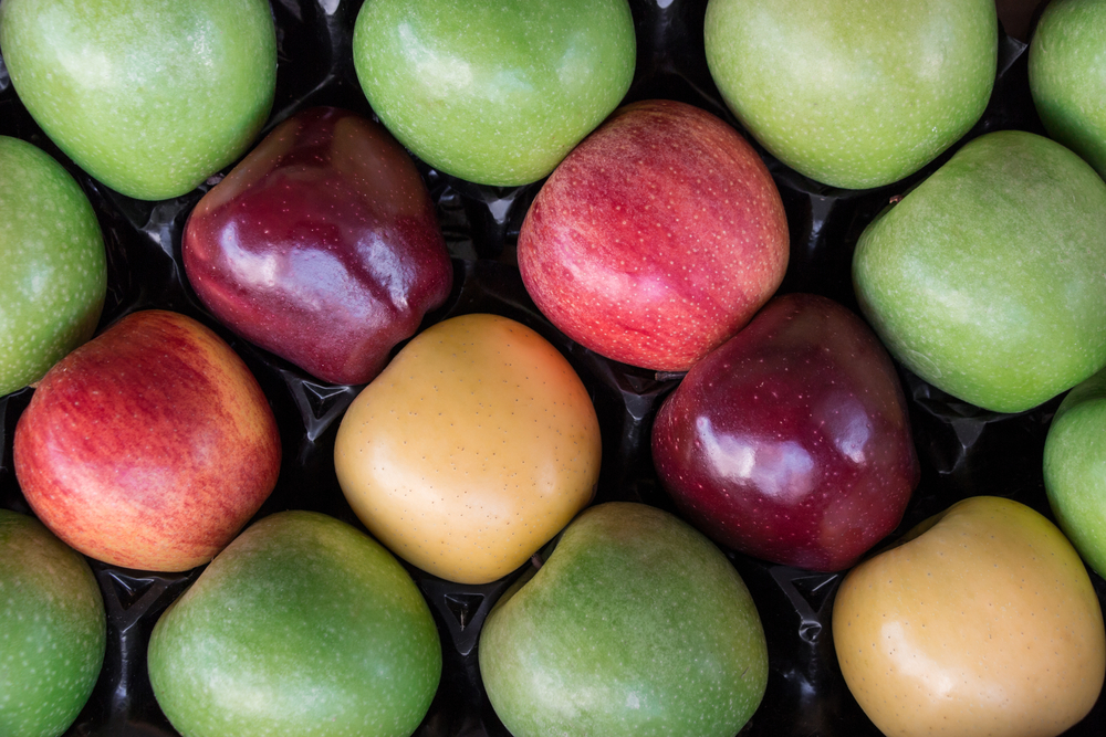 Apples granny smith, starking, gala and golden apples laid out in a row in a box at a grocery store for sale. Four different types of apples in a box for sale. Horizontal. Top view. Daylight.
