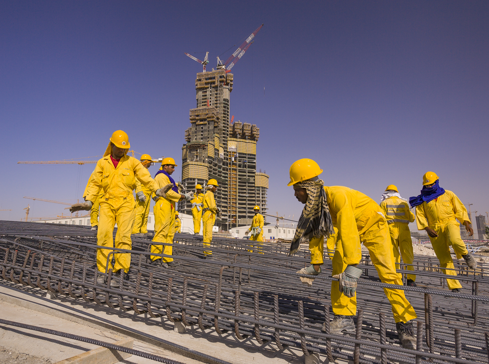 DUBAI, UNITED ARAB EMIRATES - MAY 7, 2006: South Asian immigrant contract laborers from Bangladesh, India, and Pakistan work at the construction site of Burj Khalifa, on Sheikh Zayed Road.
