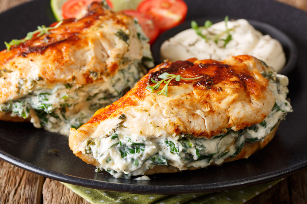 Fried chicken breasts filled with cheese and spinach, and with sauce close-up on a plate. horizontal 
