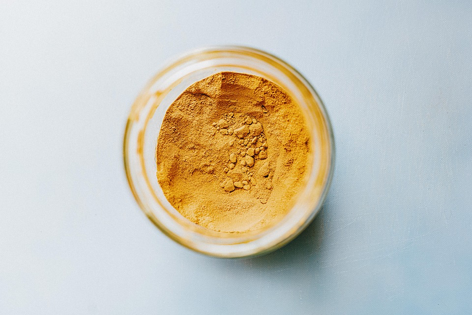 Glass jar containing bright yellow turmeric powder, a powerful anti-inflammatory spice that works similarly to natural antidepressant medicine.