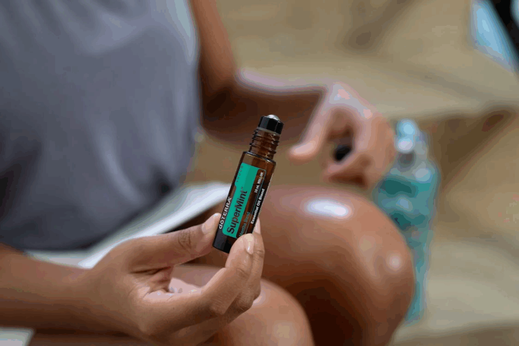 Close-up of Woman Holding a Glass Bottle of Peppermint Essential Oil with a Rolle