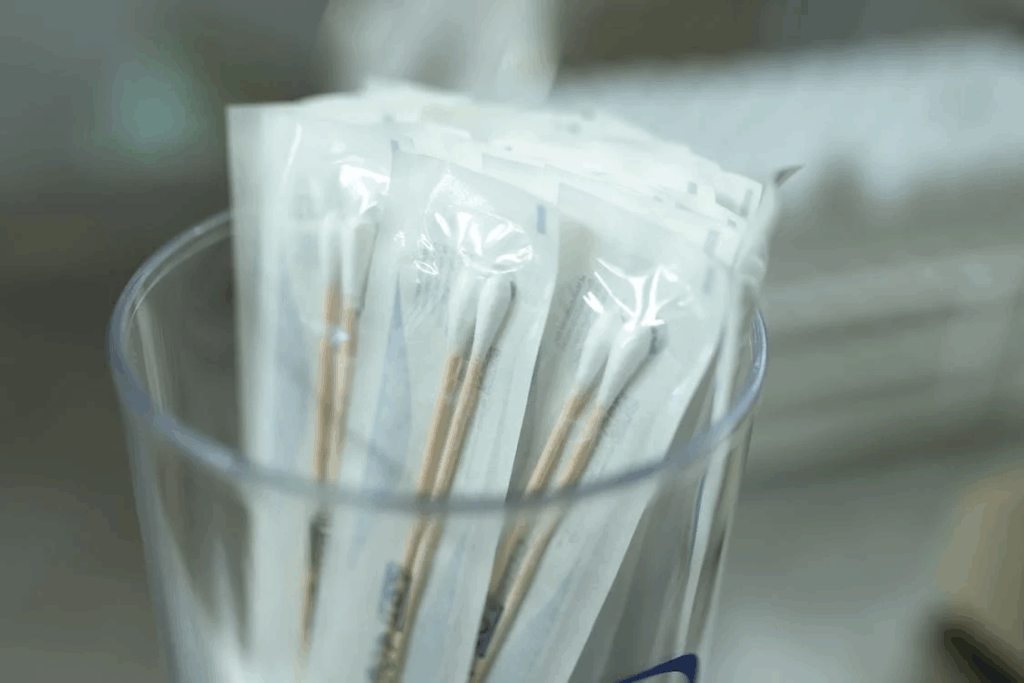 Medical testing swabs in plastic bags inside a glass container.
