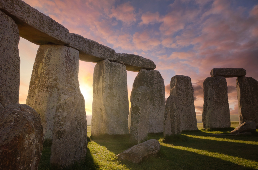 Inside the Stonehenge Circle of Stones with a Dramatic Sky Sunrise behind it

