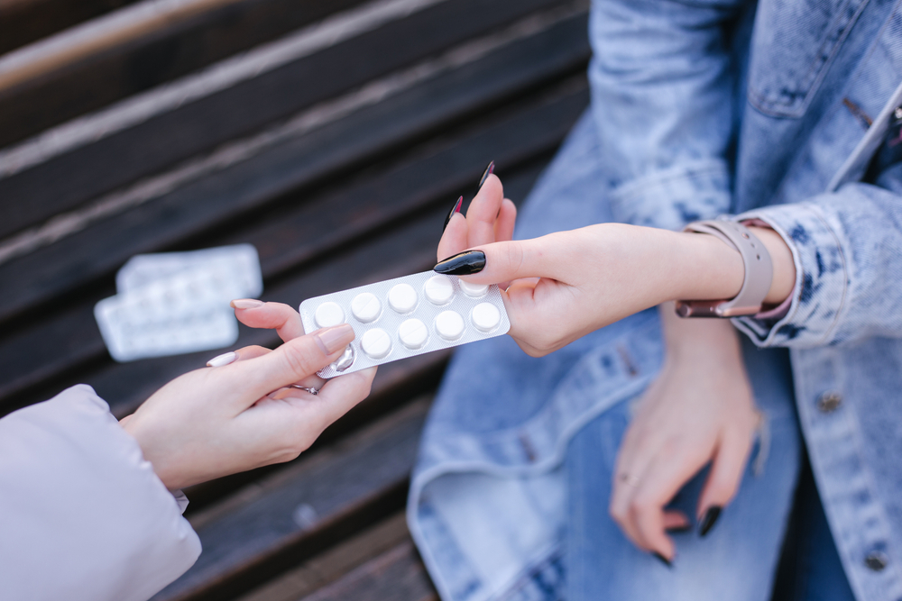 Women sharing pills in hands. Female give to woman tablets. Coronavirus theme
